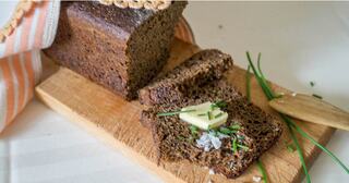 Sliced loaf of homemade bread with butter and chives