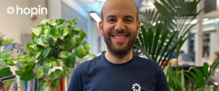 Man in Hopin t-shirt standing in front of office plants